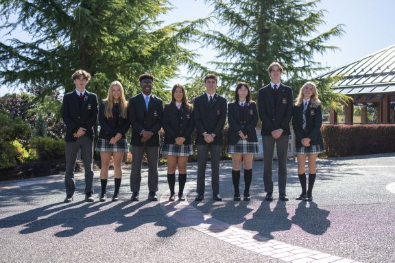 A group of students in uniform outside the theatre in the sun