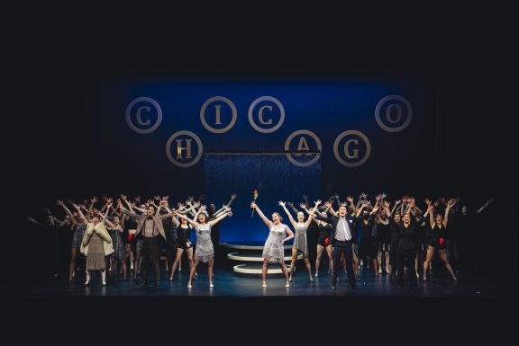 Students with their hands in the air during the musical production of Chicago