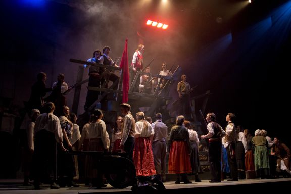 The set of Les Miz with students signing on stage